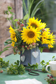 Strauß aus Sonnenblumen und Zieräpfeln in Filztasche