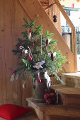 Conifer branches in old milk churn decorated with handmade pine-cone angels