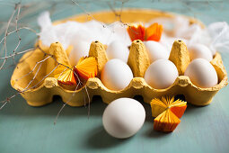 White eggs, muslin and yellow paper rosettes in yellow egg box