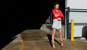 A brunette woman wearing a red leather jacket and a frayed denim skirt