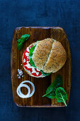 Healthy vegetarian sandwich with feta cheese, tomatoes, basil and pepper served on wooden chopping board over vintage background