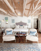 Doppelbett und zwei Sesseln in elegantem Schlafzimmer mit Dachkonstruktion aus Holz