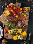 Grilled meat, corn cobs and tomato skewers