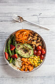 A Buddha bowl with bulgur, green asparagus, strawberries, carrots, tofu, tomatoes, sweetcorn, sweet potatoes and avocado