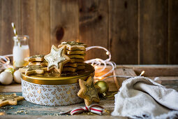 Festive star sugar cookies with golden royal icing and sprinkles with milk on golden and white cookie tin for a gift