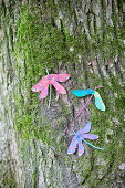 Dragonflies made from painted sycamore seeds on mossy tree