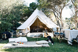 Picnic blanket with pillows in front of tent in the garden