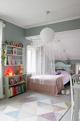Bed with canopy, book shelves, grey walls and sloping ceiling in girl's bedroom