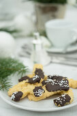 Piped biscuits with chocolate glaze on a table laid for coffee and decorated for Christmas