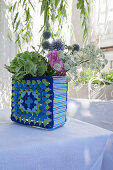 Flowers in vase with crocheted blue-and-green cover