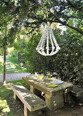 Stone bench and table below chandelier in garden