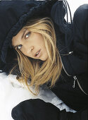 A blonde woman wearing a black winter coat in the snow