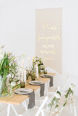 Vase of tulips, dry twigs and pillar candles on table with message on wall in background