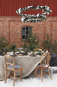 Table set for Christmas below metal wreaths outside brick house