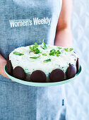 Woman holding serving platter with peppermint chocolate ice cream cake