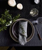 Winter table setting with fondue fork decorated with rosemary and candles