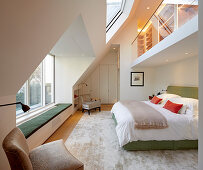 Gallery with glass balustrade in elegant, double-height bedroom