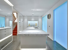Mittelblock mit Marmorplatte, verspiegelte Wände und blaue Beleuchtung in eleganter Küche