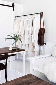 Clothes rack with white clothes next to sofa and table