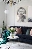 Dark blue sofa with scatter cushions, coffee table and large photos on wall in bright living room
