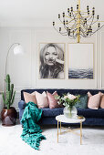 Dark blue sofa with scatter cushions below large photos on wall in bright living room