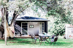 Garden table with chairs under an old tree, in the background a house with an open patio door