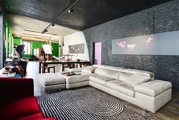 Pale leather couch below modern artwork on black wall in renovated loft apartment