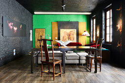 Old wooden table and chairs in renovated loft apartment with black and green walls