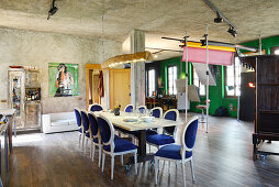 Antique chairs with velvet upholstery around long dining table in renovated loft apartment