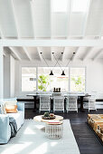 Lounge area and dark dining table with white rattan chairs in open-plan interior