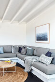 Scatter cushions on grey corner sofa in living room with white walls