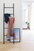 Skirt clipped to hanger on ladder and pictures leaning against wall