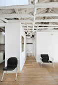 Offener Wohnraum mit Dachkonstruktion aus Holz, Raumteiler und schwarze Stühle
