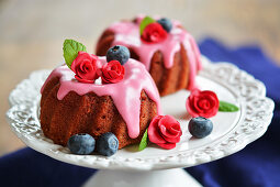 Two mini gugelhupfs with beetroot, frosting, sugar flowers, fresh blueberries and mint