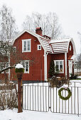 Rotes Schwedenhaus mit schneebedeckter Garten