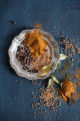 Various spices on and beside a pewter plate