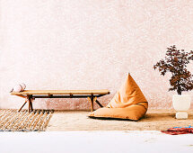 Day bed, beanbag and Japanese maple tree against a wallpapered wall