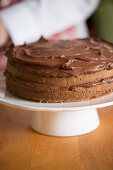 A cake being made: chocolate cream being spread onto a cake