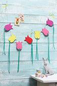 Garland of paper tulips on pale blue board wall