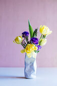 Spring flowers in vase shaped like crushed tin can
