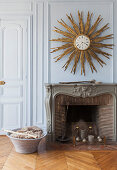 Golden sunburst mirror on wall above antique open fireplace