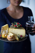 A woman holding a tray of wild herb cheese, bread and chutney