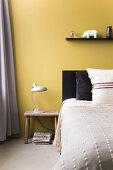 Yellow wall behind bed in bedroom