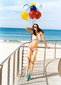 Brünette Frau mit Luftballons im Bikini am Strand
