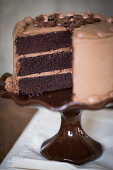 A slice of mocha cream cake on a cake stand, sliced