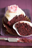 Half a chocolate cupcake with vanilla cream and a sugar rose