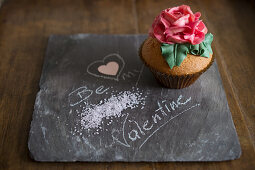 A cupcake decorated with a large sugar rose for Valentine's Day