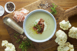 Blumenkohlsuppe mit Zutaten auf Holzuntergrund