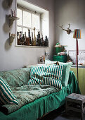 Sofas mit grünen Decken und Kissen unterm Fenster mit Figuren