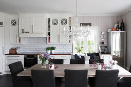 Large dining table and upholstered chairs in white country-house kitchen
